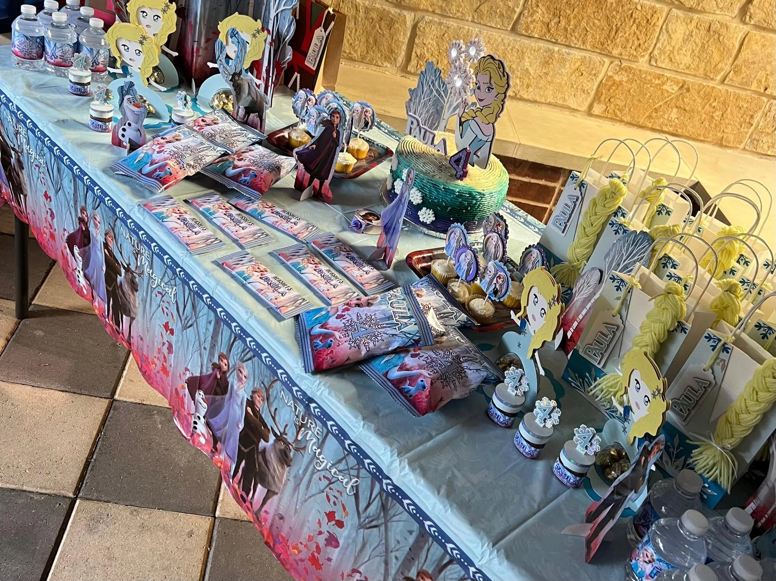 Table with Frozen-themed decorations and snacks on a stone floor.