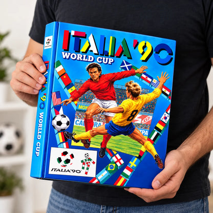 A person holds a large hardcover book titled "ITALIA '90 WORLD CUP" with colorful soccer artwork on the cover, including players, a soccer ball, and multiple national flags, against a softly blurred indoor background.
