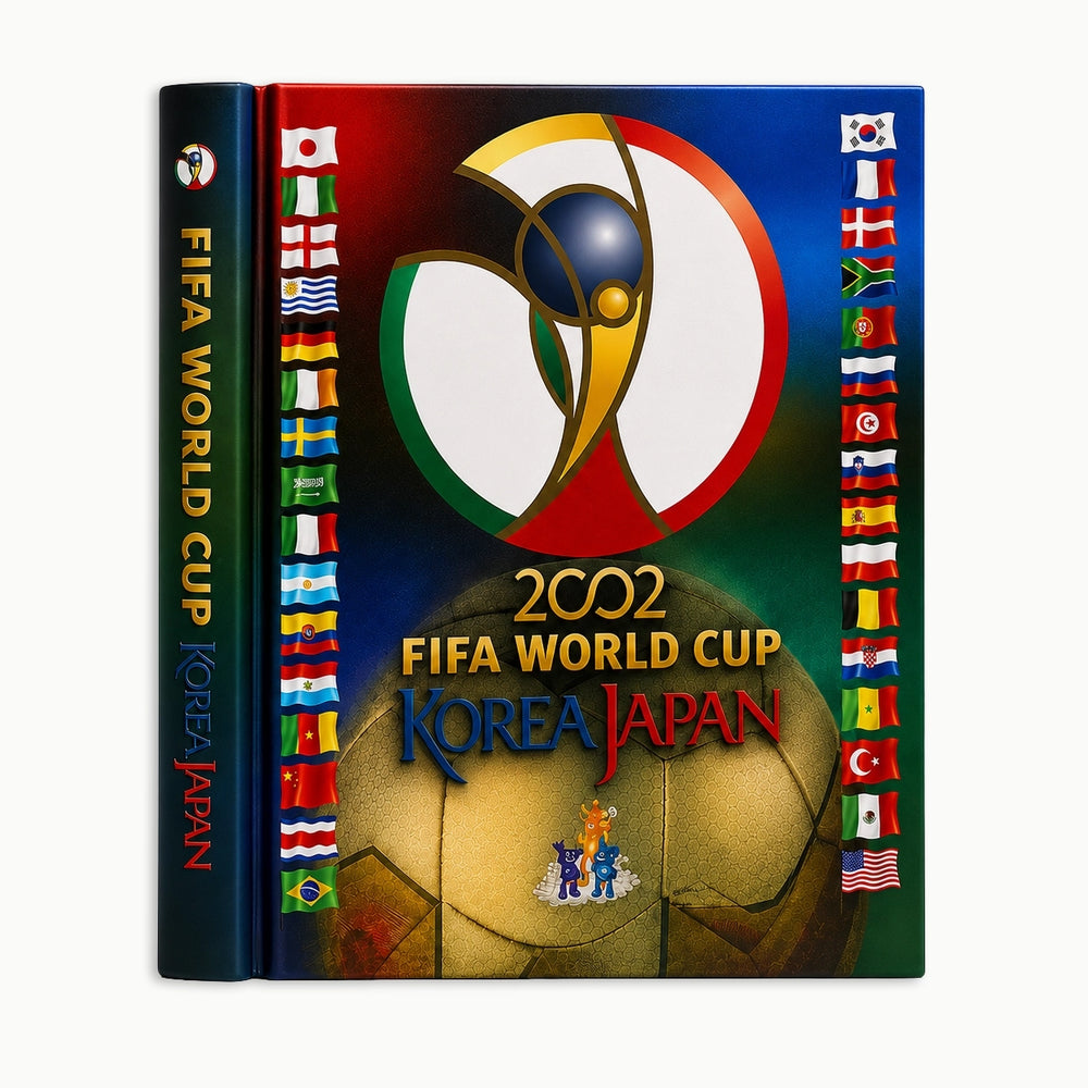 A hardcover book or album cover for the 2002 FIFA World Cup in Korea and Japan, shown upright on a light gray background. The cover features the tournament logo at the top, a large gold soccer ball at the bottom, and rows of national flags along the sides.