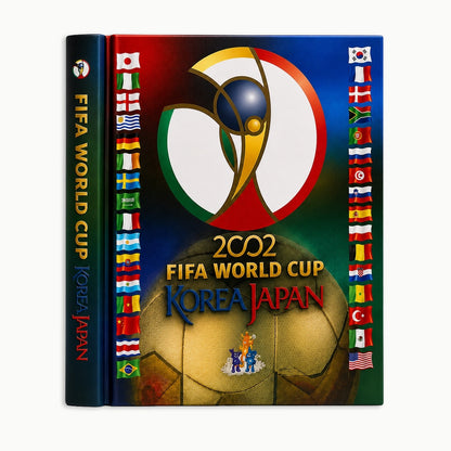 A hardcover book or album cover for the 2002 FIFA World Cup in Korea and Japan, shown upright on a light gray background. The cover features the tournament logo at the top, a large gold soccer ball at the bottom, and rows of national flags along the sides.