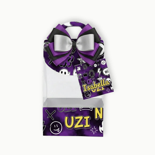 Purple hair bow with black and white accents on a clear packaging box with 'Isabella' and 'Uzi N' text.