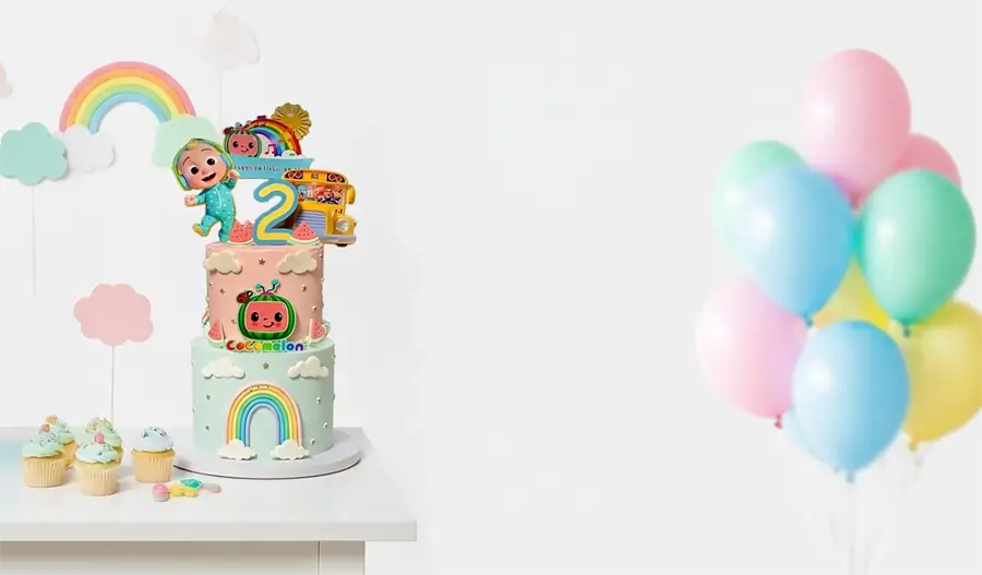 Two-tier birthday cake with colorful decorations and balloons on a white surface.