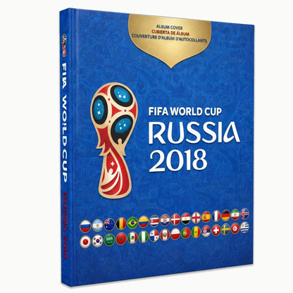 FIFA World Cup Russia 2018 official album cover shown as a 3D book mockup on a light gray background. The cover is predominantly blue with a gold badge at the top, the tournament trophy logo in the center, and the text 'FIFA WORLD CUP RUSSIA 2018' in white.